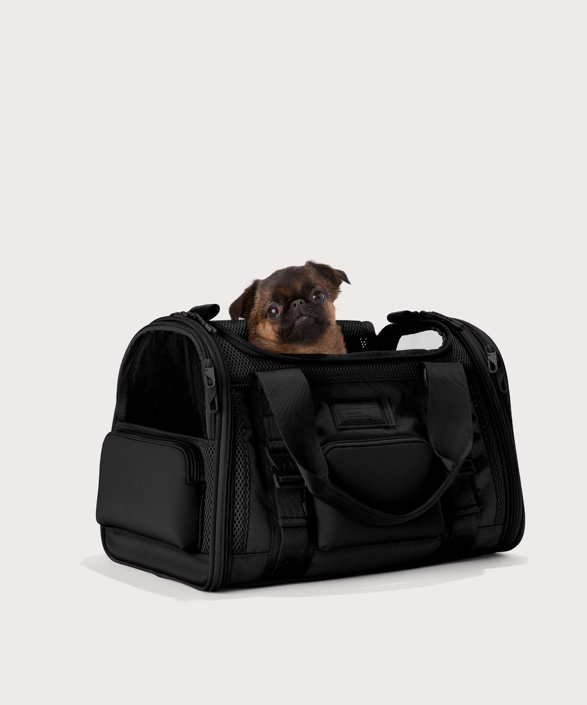 Dagne Dover Small Kyoto Pet Carrier in black seen from an angle with a dog inside the carrier. Caption: Edna is a 5-lb Brussels Griffon.